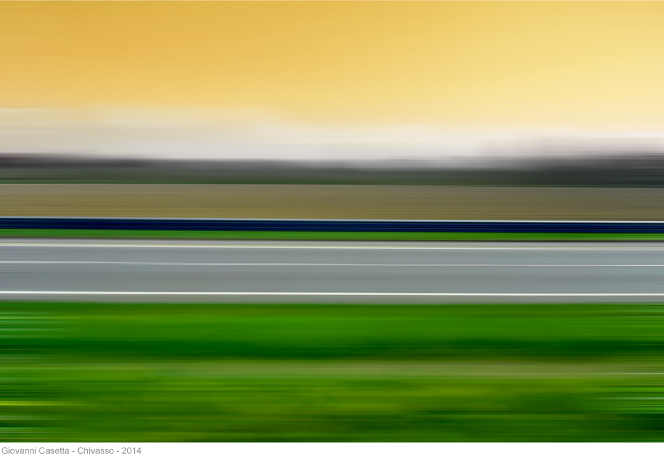 Chivasso, linee orizzontali sfocate, verde prato, strada grigia, cielo giallo